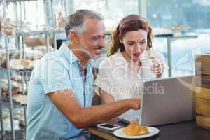 Happy couple pointing something on laptop