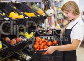 Smiling staff woman holding a box with fresh vegetables