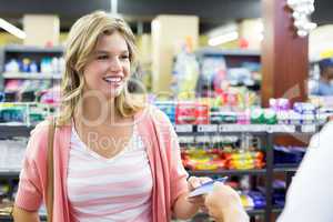 Smiling woman at cash register paying with credit card