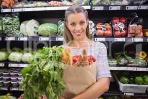 Pretty blonde holding bag with bread and vegetable