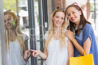 Friends finger pointing through the window shop