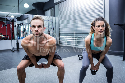 A muscular couple lifting kettlebells