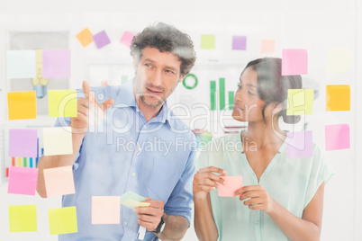 Puzzled business team looking post its on the wall