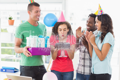 Businesswoman blowing the candles on her birthday cake