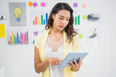 Young concentrated businesswoman holding and looking at the tabl