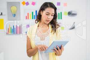Young concentrated businesswoman holding and looking at the tabl