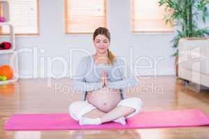 Pregnant woman doing yoga on exercise mat