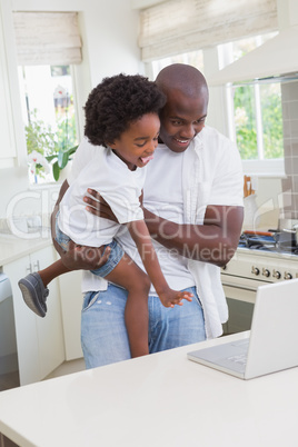 Father and son using laptop on the couch