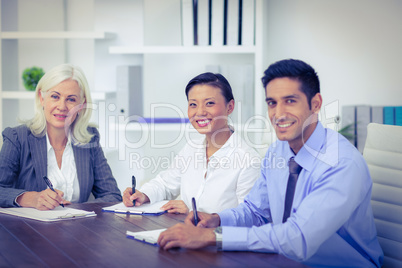 Business people writing on clipboards and looking at camera