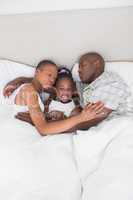 Pretty couple sleeping with their daughter in their bed