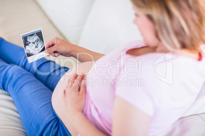 Pregnant woman looking at ultrasound scans and touching her bell