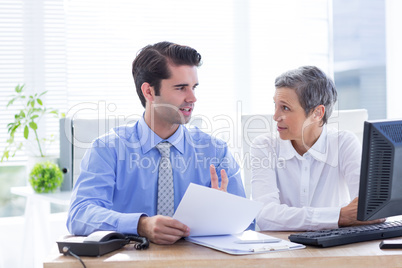 Two business people looking at a paper while working on folder