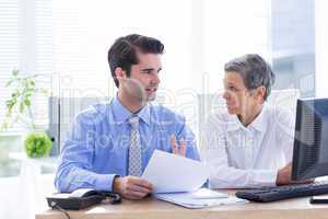 Two business people looking at a paper while working on folder