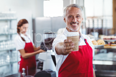 Happy barista giving take-away cup