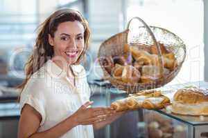 Pretty brunette smiling at camera and holding loaf of bread