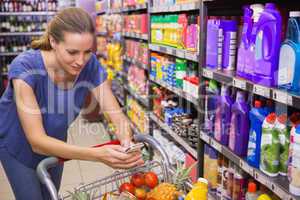 Pretty woman pushing trolley in aisle and texting