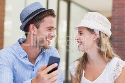 Cute couple discussing over smartphone