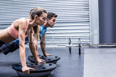 Muscular couple doing bosu ball exercises