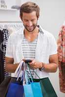 Smiling man with shopping bags using smartphone