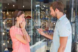 Young serious man giving jewellery to a surprised woman