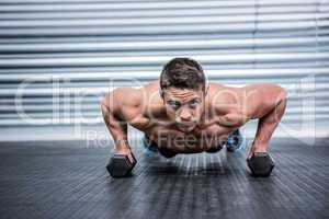 Portrait of muscular man doing push-ups with dumbbells