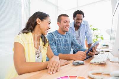 Smiling coworkers using tablet computer together