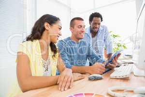 Smiling coworkers using tablet computer together