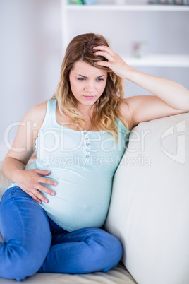 Pregnant woman having headache on couch