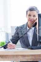 Smiling portrait of a businesswoman phoning and writing