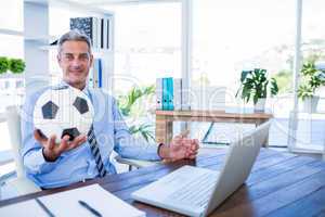 Happy businessman looking at camera and holding foot ball