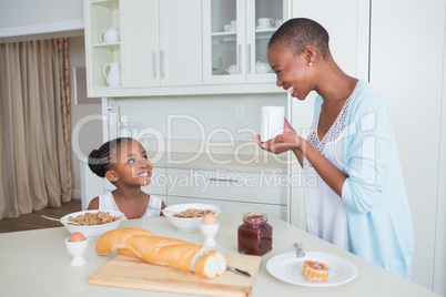 Smiling mother and daughter eating together