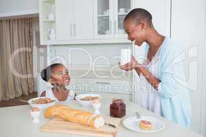 Smiling mother and daughter eating together