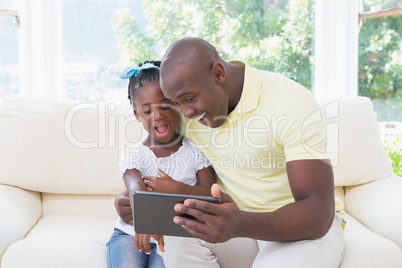 Happy smiling father using digital tablet with her daughter on c