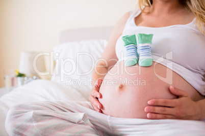 Pregnant woman with baby shoes over bump