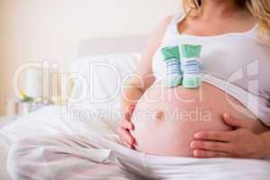 Pregnant woman with baby shoes over bump