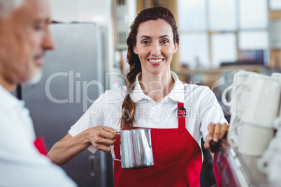 Pretty barista looking at camera and using the coffee machine