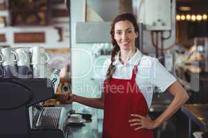 Pretty barista looking at camera and using the coffee machine