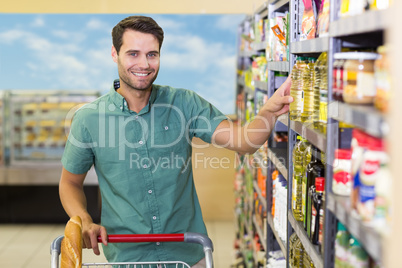 Portrait of smiling man taking oil in the shelf of aisle