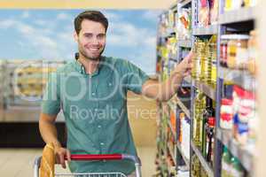 Portrait of smiling man taking oil in the shelf of aisle