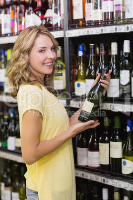 Portrait of a smiling pretty blonde woman having a wine bottle i