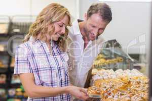 Smiling casual couple taking a pastry