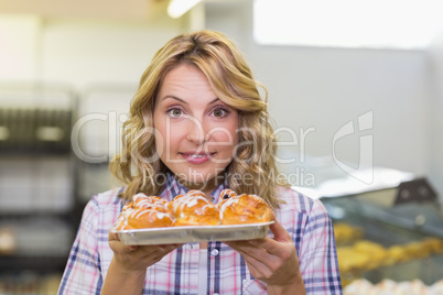 Portrait of a smiling blonde woman showing a pastry