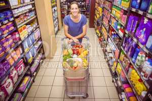 Pretty woman pushing trolley in aisle