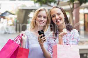 Happy women friends smiling at camera with shopping bags
