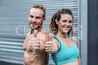 Muscular couple gesturing thumbs up