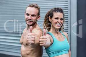 Muscular couple gesturing thumbs up