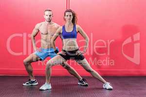 Muscular couple doing leg stretching