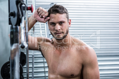 Portrait of muscular man leaning against gym equipment