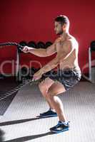 Muscular man exercising with rope