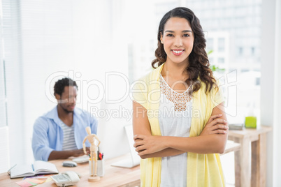 Smiling woman posing in front of her colleague with arms crossed